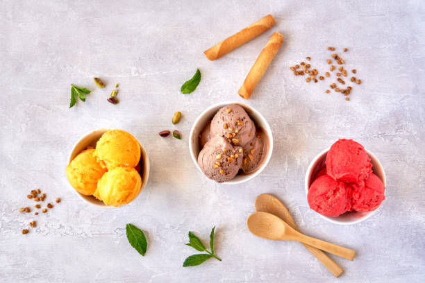 istock Ice cream scoops in bowls with chocolate , strawberry and mango flavors. Top view 1247945191