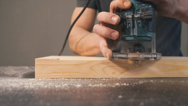 istock Man cut wooden chamfer by handy machine in workshop. 1247950181
