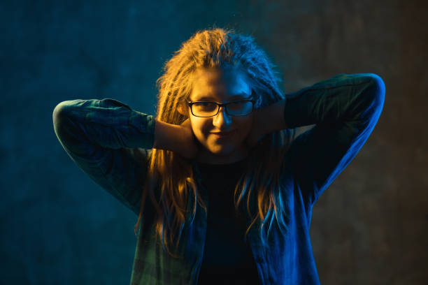 istock Girl in glasses with colored lighting on dark background. 1247950182