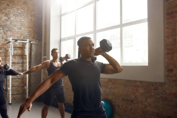 istock Prepare hard. Athletic man lifting dumbbell while having workout at industrial gym. Group training, teamwork concept 1247964932