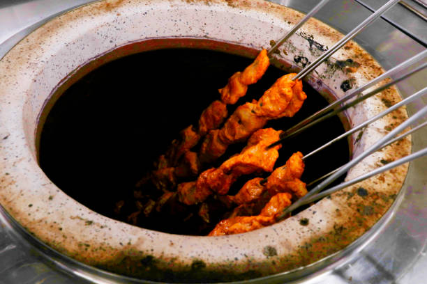 cubetti di pollo marinati con spezie (pollo tikka) spiedini che cucinano in un forno di argilla noto come tandoor - chicken tandoori foto e immagini stock