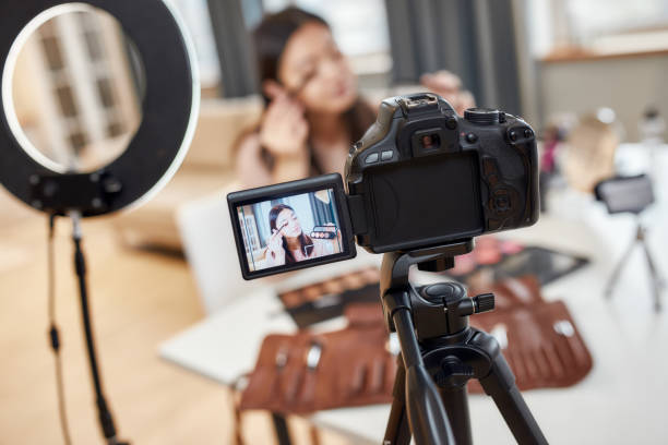 istock Engage with the world. Asian female blogger applying makeup while recording a tutorial video for her beauty blog using camera at home 1247972152
