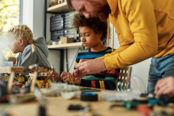 istock Converting dreams into reality. Young technicians building a robot, working with a wiring kit together with a male teacher at a stem robotics class. Inventions and creativity for kids 1247979463
