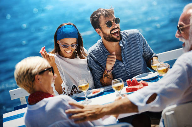 Family on a sailing cruise. Closeup side view of a senior couple having lunch with their son and his fiancee while sailing during their summer vacation. cruise ship people stock pictures, royalty-free photos & images