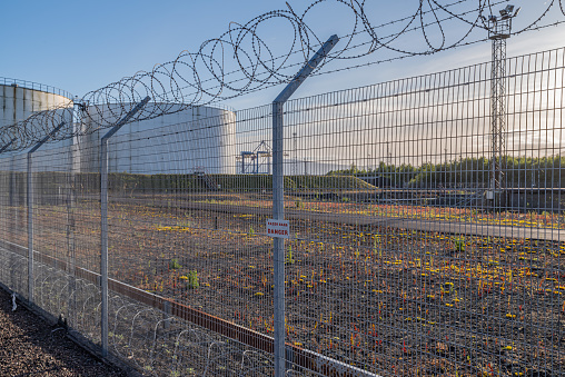 Steel fence, topped with razor wire, protecting a fuel storage facility.  Belfast, Northern Ireland.