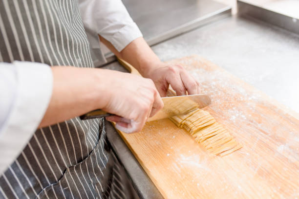 istock Cut noodles on kitchen . Chef cooks spaghetti in restaurant. Chef cuts with a knife raw noodles with flour 1247987980