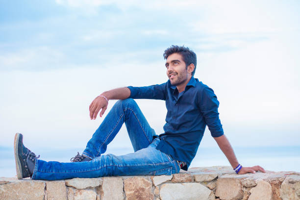 istock Man thinking looking to blue sky while sitting on a concrete bridge above the sea 1247988733