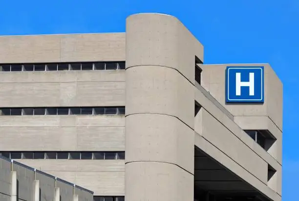 large modern building with blue letter H sign for hospital