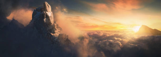 Beautiful aerial landscape of mountain peak at sunset above the clouds - panoramic stock photo