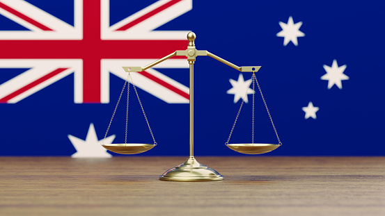 Bronze scale standing in front of Australian flag. Horizontal composition with copy space. Front view. Social justice concept.