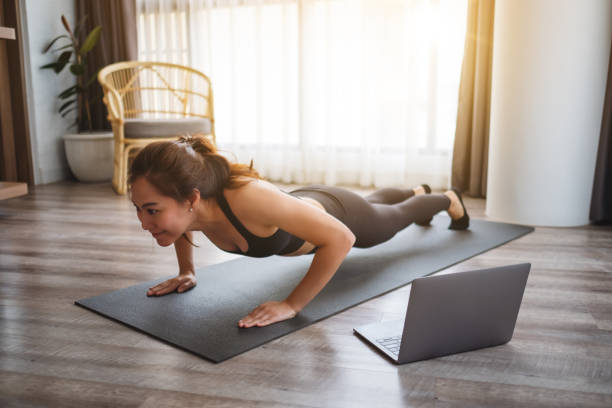 istock A beautiful young woman doing push ups on training mat while watching online workout tutorials on laptop at home 1248055676