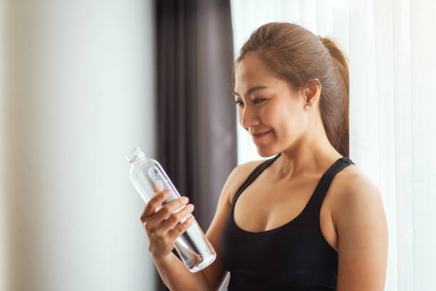 istock A beautiful woman holding and looking at a water bottle while working out 1248055709
