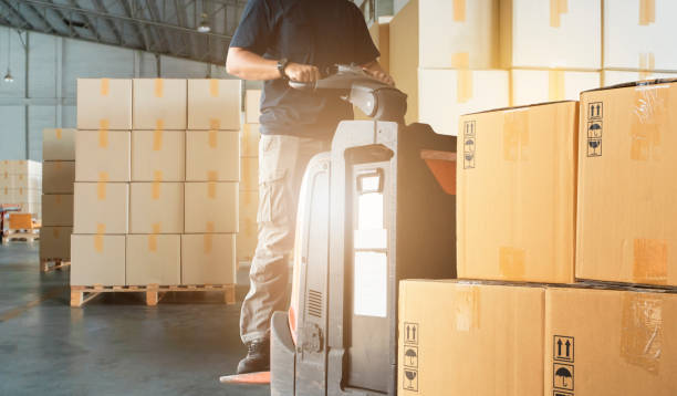 istock Interior of warehouse storage. Worker courier driving electric forklift pallet jack loading shipment boxes 1248064280