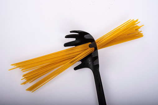 Spaghetti dry through black spoon.