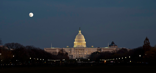 The United States Capitol is the meeting place of the United States Congress, the legislature of the Federal government of the United States. Located in Washington, D.C., it sits atop Capitol Hill at the eastern end of the National Mall. At night with lighting and the moon.