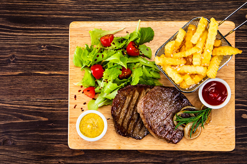 Grilled steak with sunny side up egg, french fries and vegetable salad