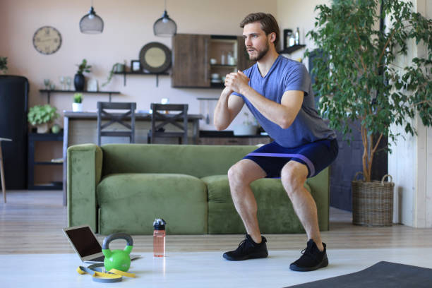 istock Handsome man doing squats exercise at home during quarantine. Concept of healthy life. 1248092892