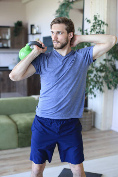 istock Handsome man focused on lifting a dumbbell during an exercise at home during quarantine. 1248092901