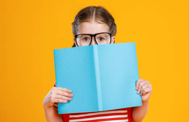 istock Schoolgirl hiding face behind textbook 1248102034