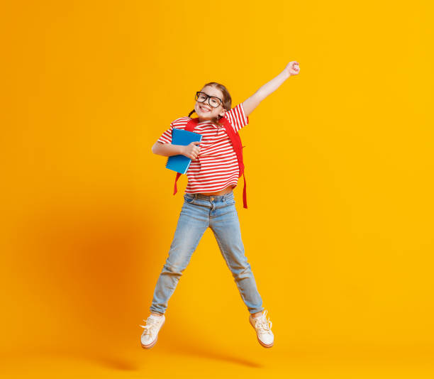 istock Happy school girl jumping with raised arm 1248103097