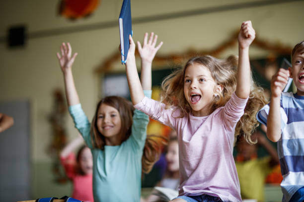 istock Group of joyful elementary students jumping in the classroom. 1248118468