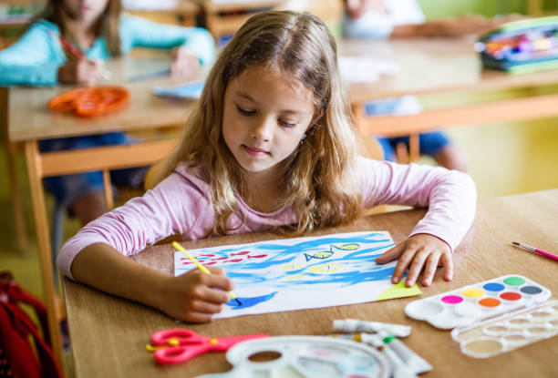istock Elementary student painting on a paper during an art class in the classroom. 1248120729