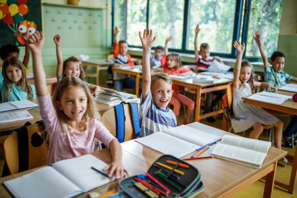 istock Large group of elementary students raising their arms on a class. 1248122461