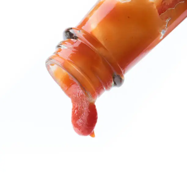 Photo of Tomato ketchup falling from bottle on white background