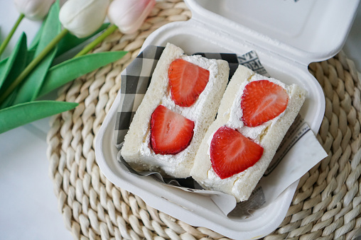 A white bread with fresh whipping cream and fresh strawberry.