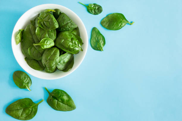 Fresh spinach i Fresh spinach in a bowl on a blue background spinach photos stock pictures, royalty-free photos & images