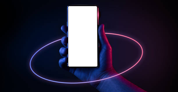 Phone in hand Phone in hand. Silhouette of male hand holding bezel-less smartphone with futuristic neon light circle on dark background. Screen is cut with clipping path. mobile phone lights up stock pictures, royalty-free photos & images