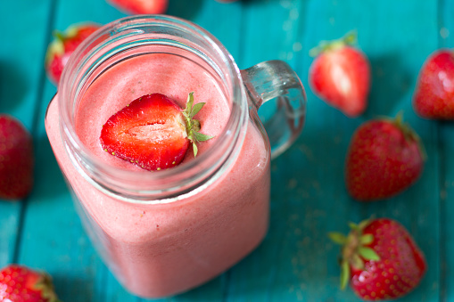 Fresh strawberry smoothie on blue table.