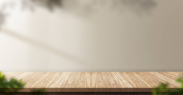 istock wood table background with sunlight window create leaf shadow on wall with blur indoor green plant foreground.panoramic banner mockup for display of product,warm tone lights 1248126119