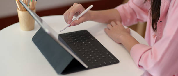 istock Female college student using digital tablet while sitting at coffee table in living room 1248128999