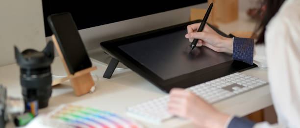 istock Graphic designer working on drawing tablet with stylus pen, computer and supplies on white office desk 1248129014