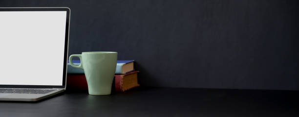 istock Simple workspace with coy space, mock-up laptop, mug and books on black table 1248129064
