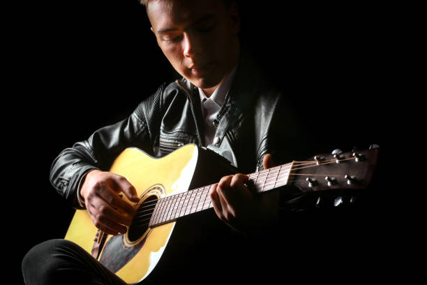 istock Young men playing the guitar with black background 1248130980