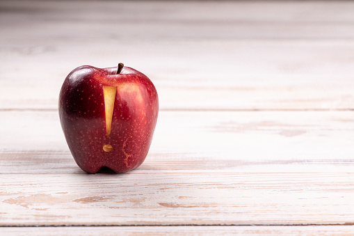 Close-up image of a vibrant red coloured juicy apple precisely carved with exclamation mark sigh placed on white bleached pine floor boards in studio. Ideal for many concept with plenty of copy space for your message and ideas: Ripe Fruit, Healthy Lifestyle, Warning sigh, Healthcare And Medicine, Carving - Craft Product. Shot on Canon EOS R with premium lens for highest quality.