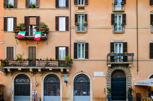 Florence, Italy - April 13, 2023: Balcony almost at the corner of the facade of a townhouse in the old town. The windows in this building are equipped with shutters.