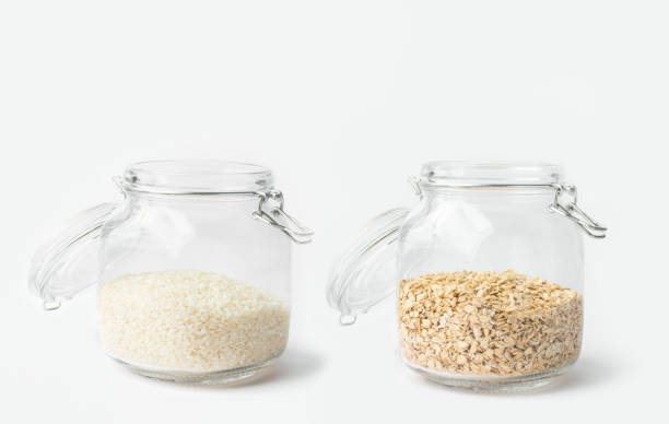 istock Glass jars with lid filled with dry grains rice oats on white table. Kitchen storage solutions 1248135723