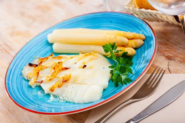 Appetizing roasted halibut fillet with baked white asparagus. Seafood delicacy