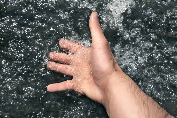 istock A man dips his hand in a stream of creek. 1248141863