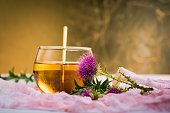 Milk thistle herbal tea and flower isolated against golden background