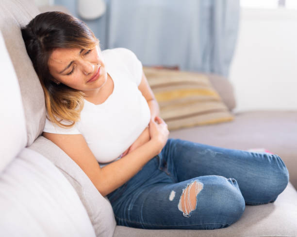 mexican female at sofa holding hands on the illness stomache - colic imagens e fotografias de stock