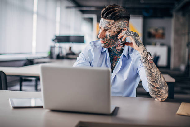 istock Modern businessman with whole body covered in tattoos using smart phone in office 1248146128