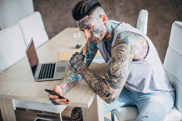 istock Man with whole body covered in tattoos using smart phone 1248147974