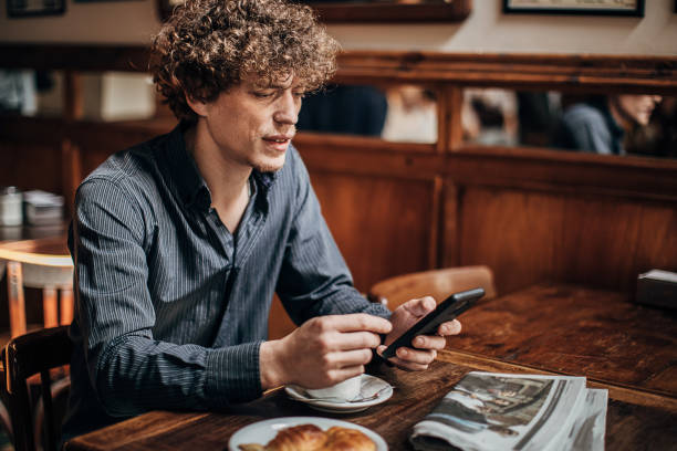 joven usando teléfono inteligente en la cafetería - croissant telephone coffee shop on the phone fotografías e imágenes de stock
