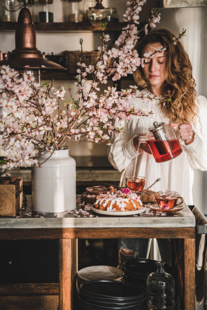 istock Young woman pouring tea over table with spring bundt cake 1248158290
