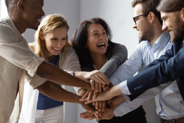 Overjoyed multiethnic businesspeople stack palms together celebrating promotion and reward Close up image overjoyed 5 multi ethnic business people stack touch arms palms together celebrating promotion reward, succeed common aim. Give high five symbol of unity, team building activity concept high fidelity stock pictures, royalty-free photos & images