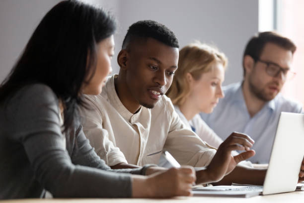 multiethnic colleagues seated in coworking room discuss new corporate app - trainee imagens e fotografias de stock